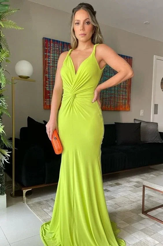 Woman in a bright green evening dress holding an orange clutch, modern living room setting