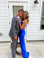 Smiling couple posing outside, woman in a blue ZAPDRESS gown, man in a gray suit