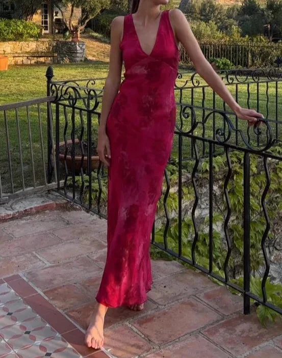 Woman in a sleeveless red maxi dress from ZAPDRESS standing on a patio with garden background.