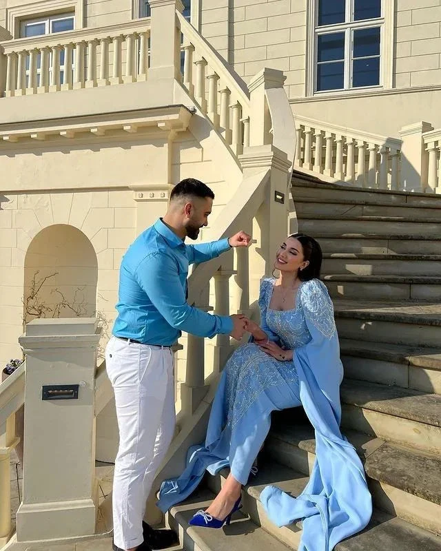 Elegant couple posing on outdoor staircase, woman in blue gown, man in blue shirt, ZAPDRESS style