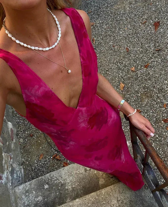 Woman in a vibrant pink sleeveless Zapdress dress with pearl jewelry on outdoor steps
