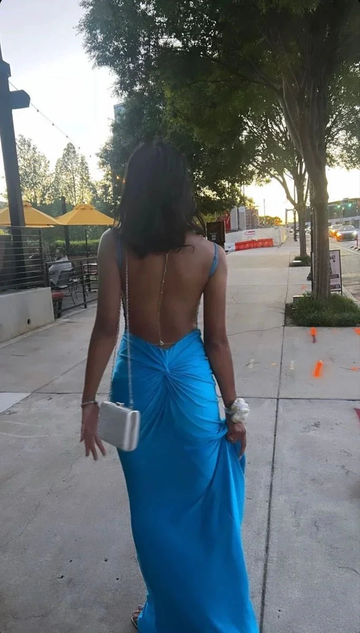 Woman in open-back blue evening dress walking on city sidewalk, ZAPDRESS fashion