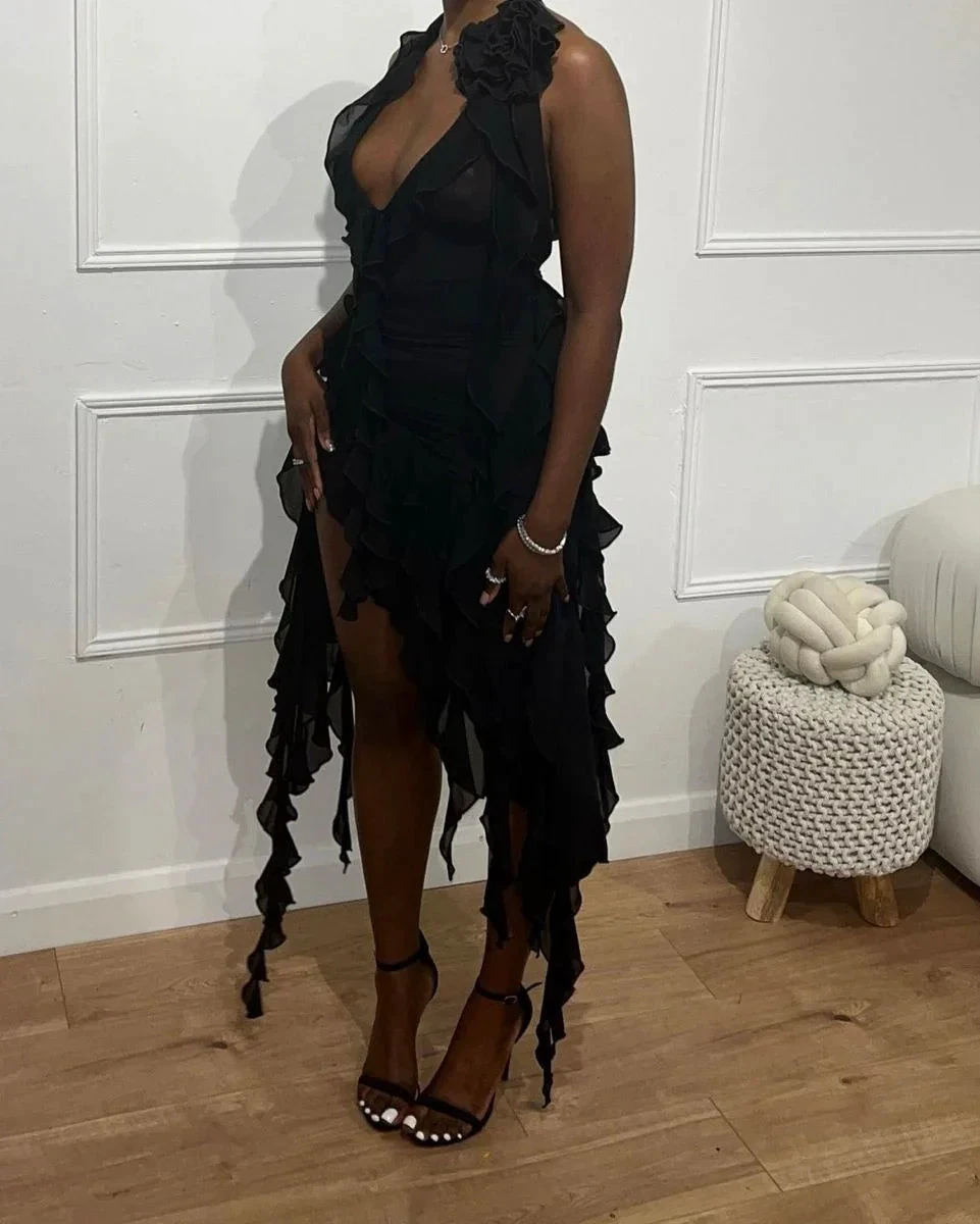Woman wearing a ruffled black dress and heels, standing indoors at ZAPDRESS