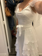 Woman wearing elegant white ruffle dress with waist tie from ZAPDRESS in indoor setting