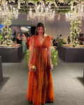 Woman in an elegant orange dress at a floral, chandelier-lit event, ZAPDRESS fashion