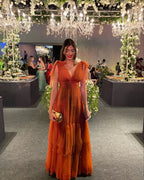 Woman in elegant orange evening dress at a floral chandelier decorated event, ZAPDRESS style