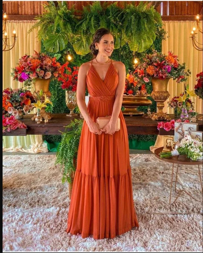 Woman in an orange maxi dress at floral event with lush greenery, ZAPDRESS elegant style
