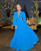 Woman in a flowing blue evening gown at floral event, ZAPDRESS fashion style