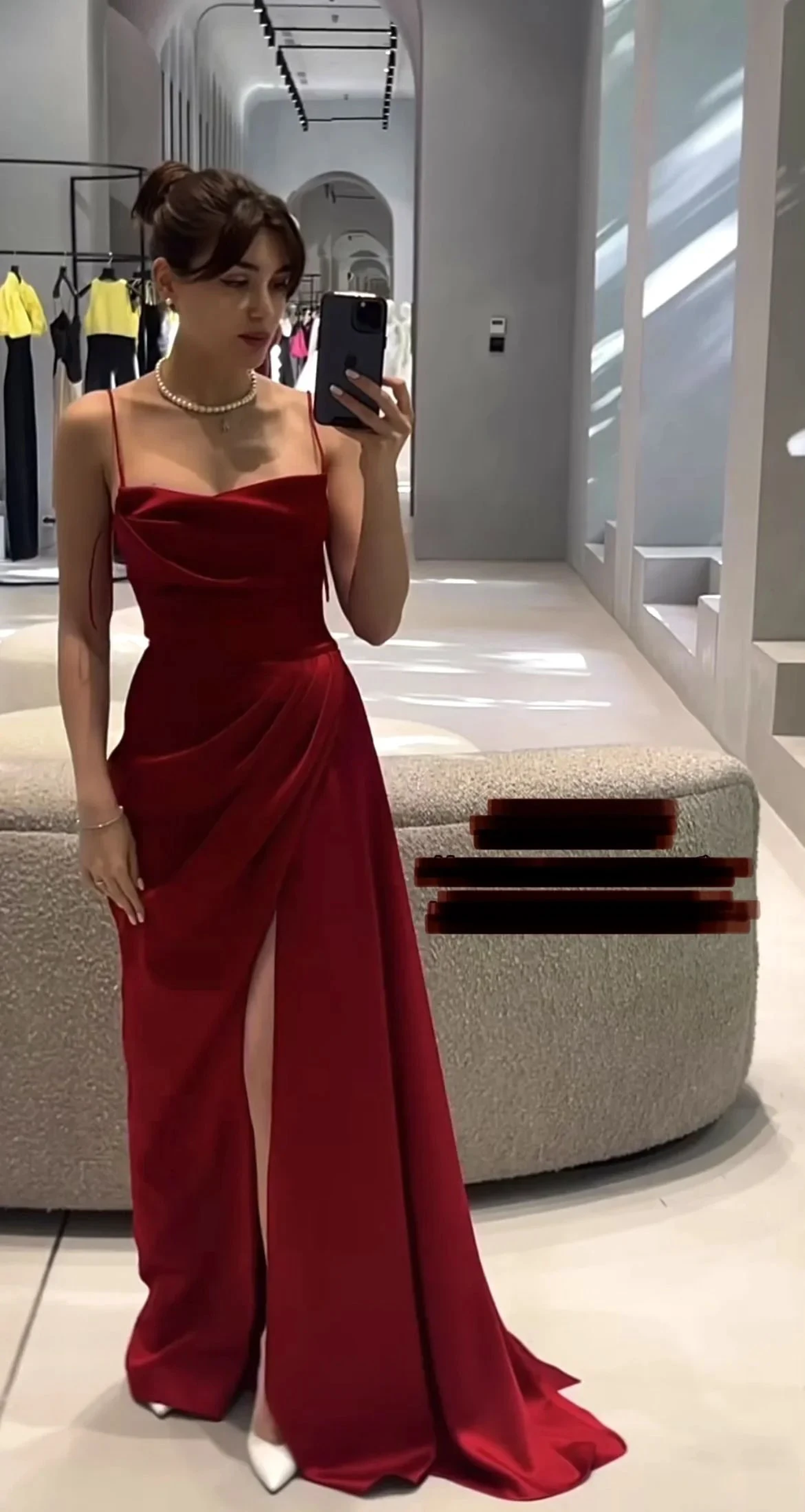 Woman in elegant red evening dress with thigh-high slit, posing in modern boutique