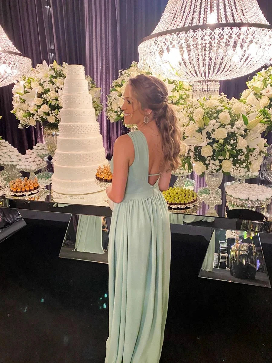 Woman in light blue formal dress at elegant event with large cake, flowers, and chandeliers