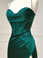 Emerald green satin evening dress with draped bodice and side slit, displayed on mannequin