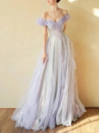 Elegant woman in sparkly off-shoulder lilac tulle gown from ZAPDRESS, standing indoors