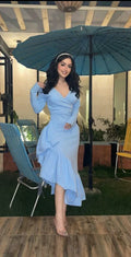 Woman in elegant light blue dress with ruffled hem posing outdoors at night under umbrella