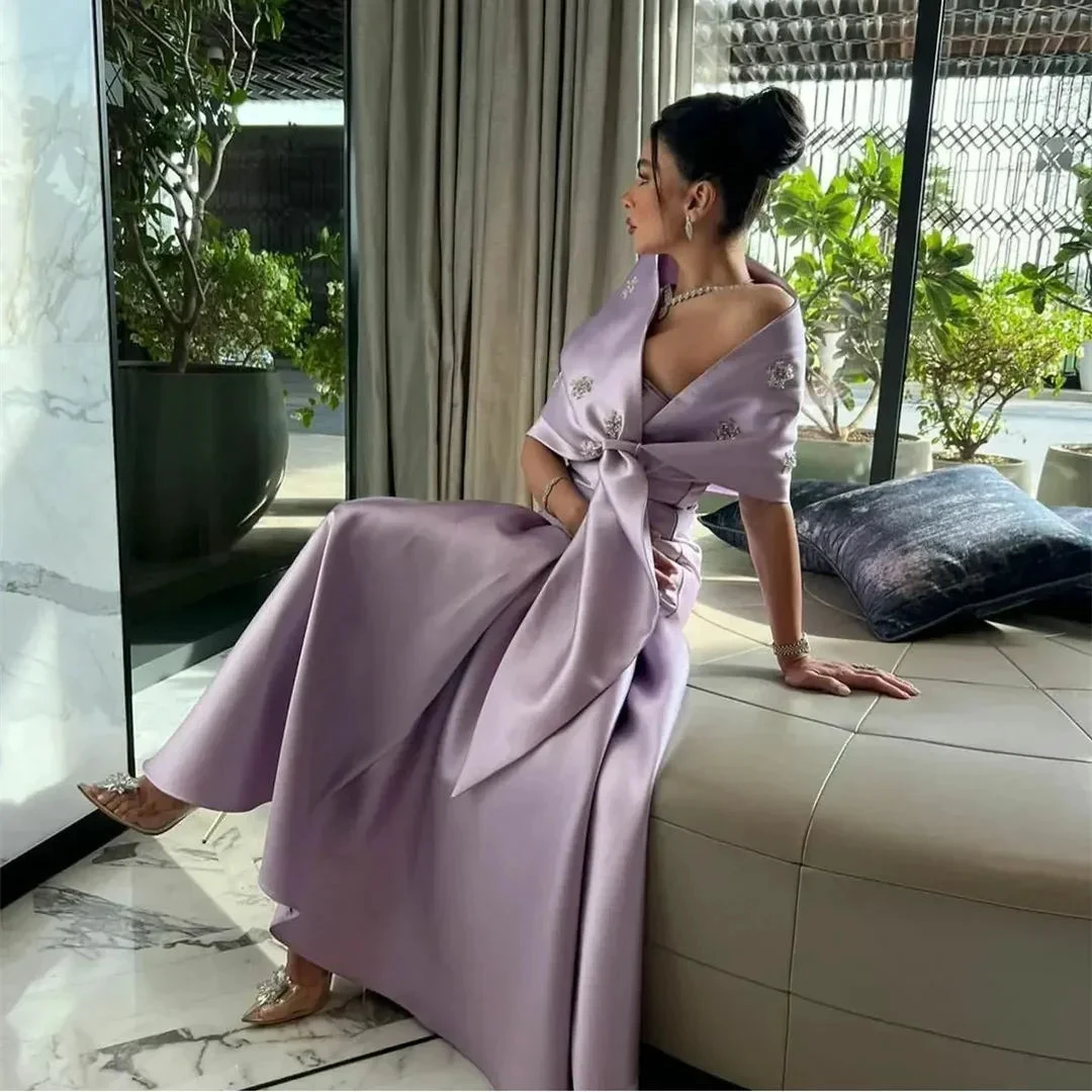 Woman in elegant lavender satin gown with embellished details sitting indoors by large window, ZAPDRESS fashion