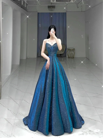 Elegant woman in a sparkling blue evening gown stands in a modern, minimalist room for ZAPDRESS