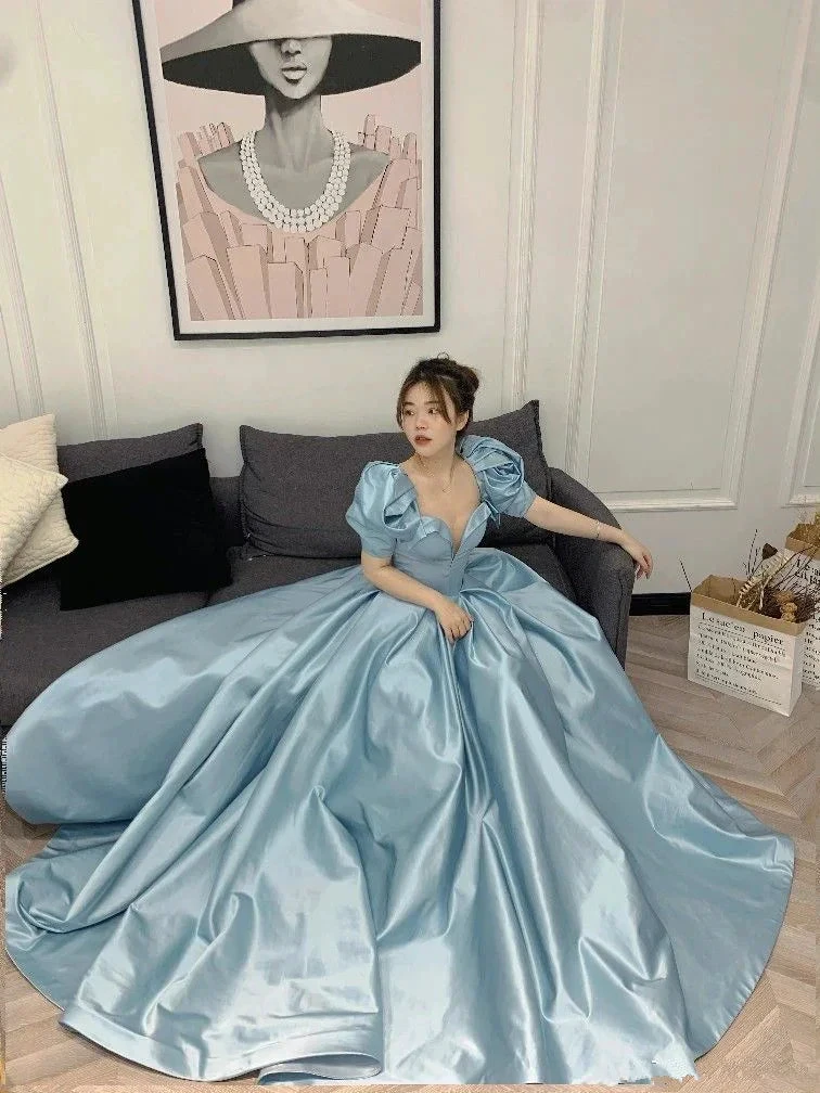 Woman in a blue satin ball gown sitting on a couch, elegant dress by ZAPDRESS