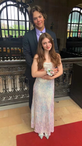 Young couple in formal attire posing at an elegant venue, woman in iridescent ZAPDRESS gown