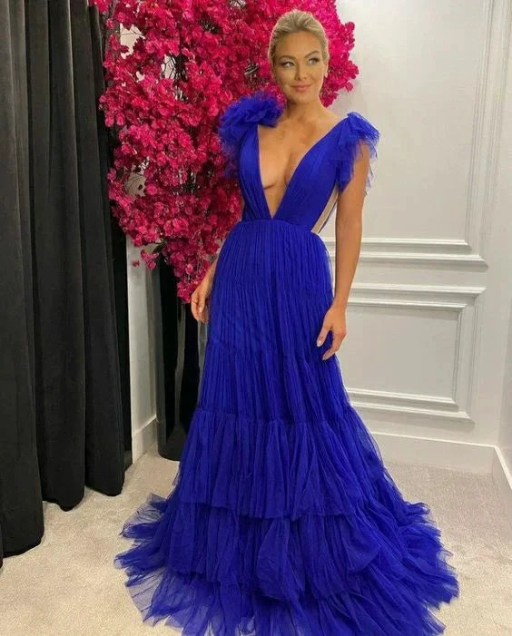 Woman in an elegant royal blue evening gown with tulle layers, posing by pink flowers at ZAPDRESS