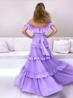 Woman twirling in a tiered lavender ruffle dress, Zapdress fashion in modern living room
