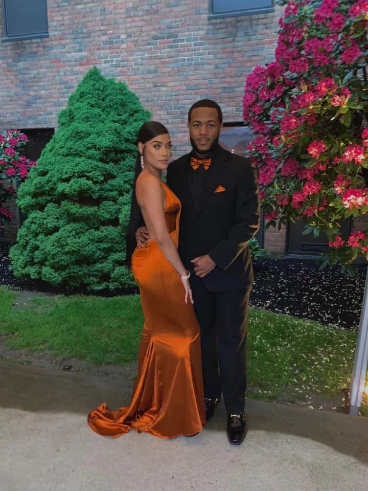 Elegant couple posing outdoors, woman in shiny orange gown, ZAPDRESS fashion style