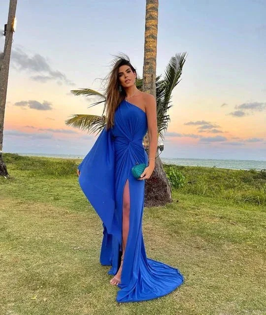 Woman in vibrant blue evening gown with slit on grass by palm trees at sunset, ZAPDRESS fashion