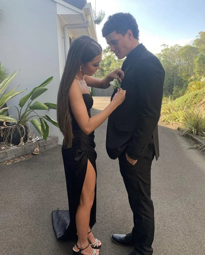 Young couple in formalwear, woman in black dress, man in suit, outdoors by house