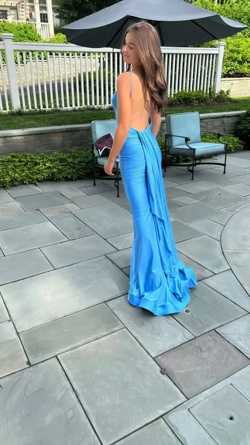 Woman in elegant blue backless gown outside, ZAPDRESS fashion, patio setting