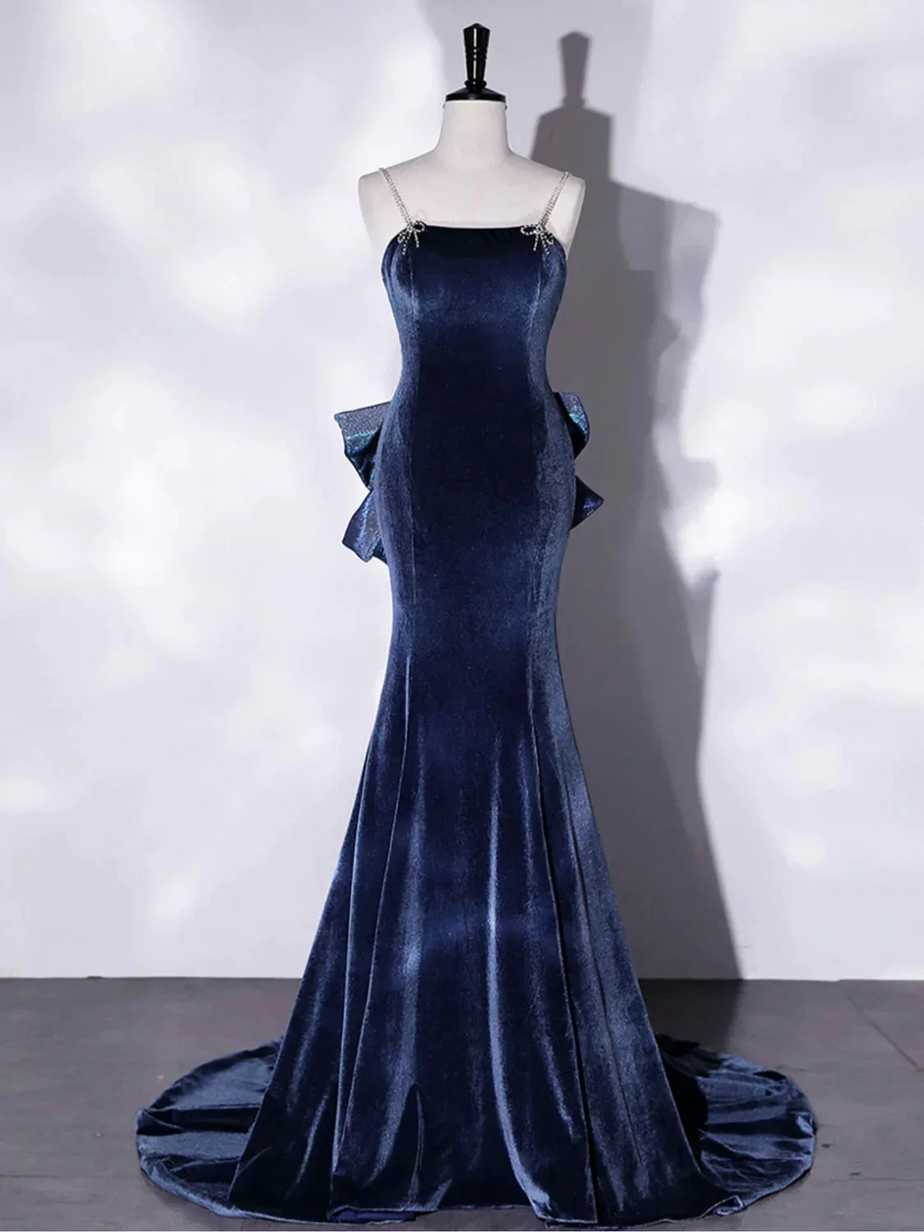 Elegant navy blue velvet evening gown with straps and ruffled sides on mannequin at ZAPDRESS