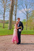 Young couple in formal attire, pink dress and black suit, posing outdoors at ZAPDRESS event.