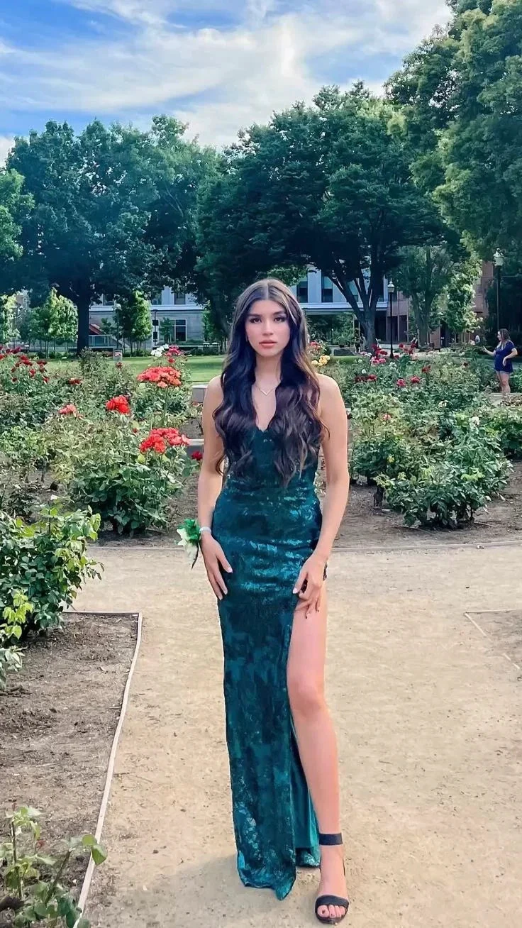 Woman in emerald green formal dress posing in garden, surrounded by roses, ZAPDRESS fashion