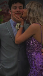 Couple in formal wear, man in gray suit and woman in purple sequin dress, prom pose