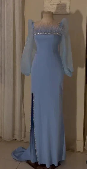 Elegant long blue evening dress with sheer puff sleeves and jeweled neckline, displayed indoors