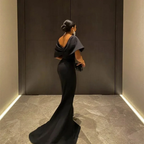 Elegant woman in a black evening gown with open back at ZAPDRESS, standing indoors