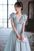 Elegant woman in powder blue evening gown with bow shoulders from ZAPDRESS, holding clutch