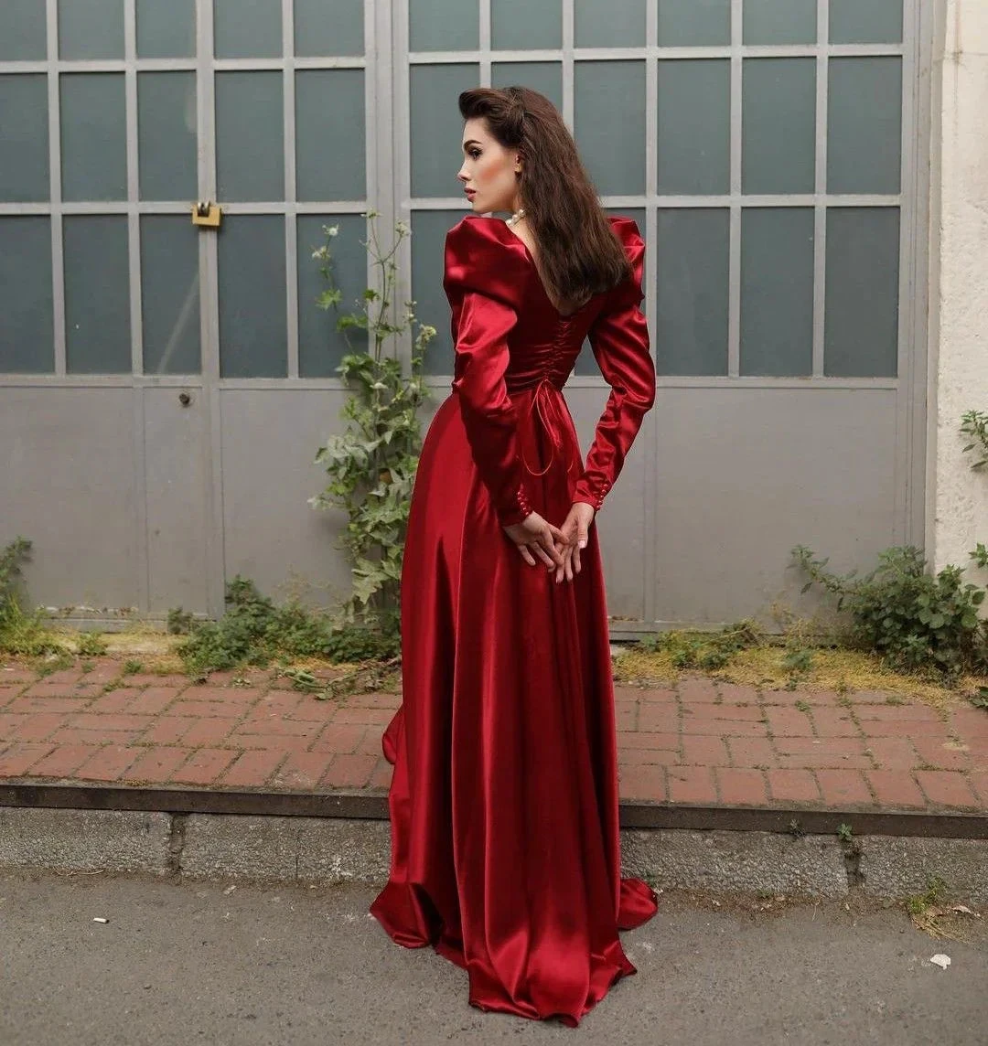 Woman in elegant long red satin dress standing outdoors by industrial doors, ZAPDRESS fashion