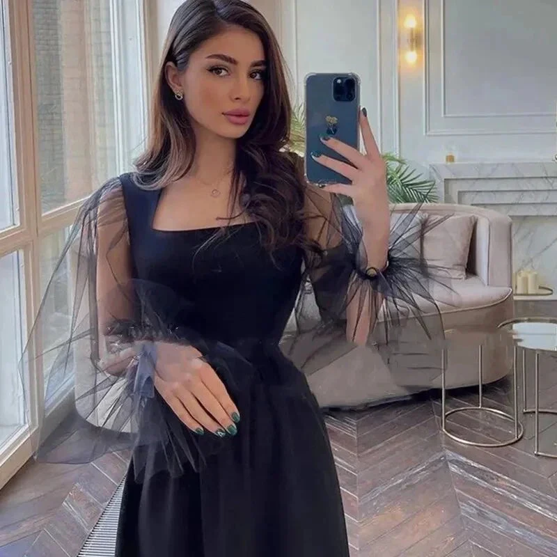 Woman in modern living room wearing elegant black tulle sleeve dress, taking selfie for ZAPDRESS