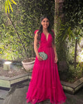 Woman in a vibrant pink evening dress holding a green clutch, standing outdoors with greenery, ZAPDRESS style
