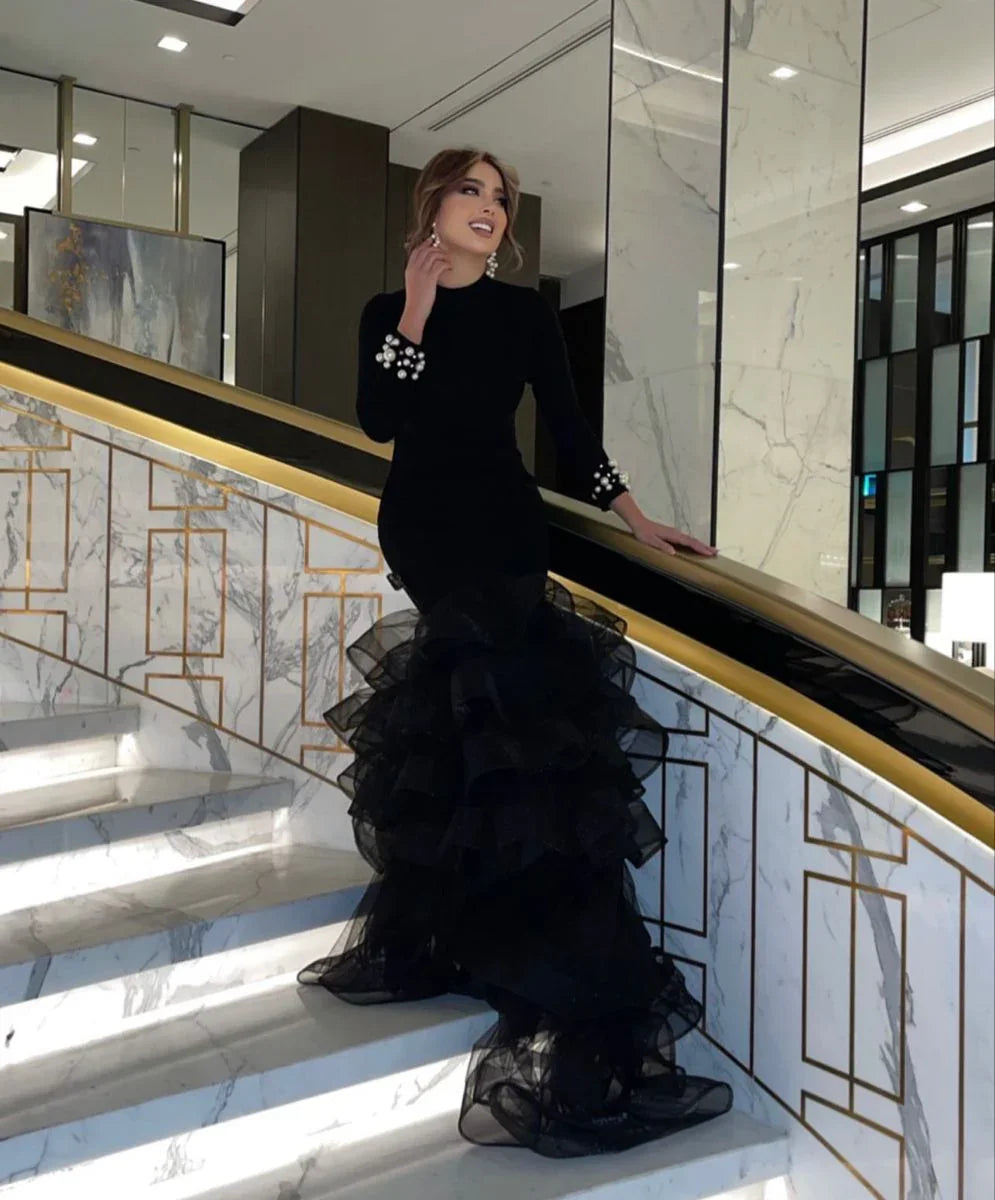 Woman in elegant black ruffled evening dress on marble staircase, ZAPDRESS fashion