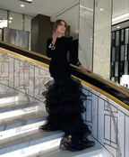 Woman in elegant black ruffled evening dress on marble staircase, ZAPDRESS fashion