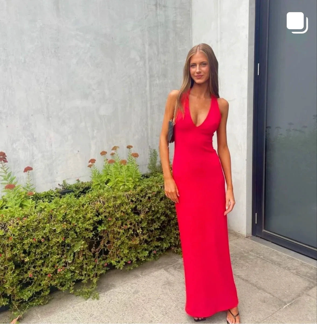 Woman in a vibrant red maxi dress standing outdoors by a modern concrete wall, ZAPDRESS fashion