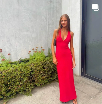 Woman in a vibrant red maxi dress standing outdoors by a modern concrete wall, ZAPDRESS fashion