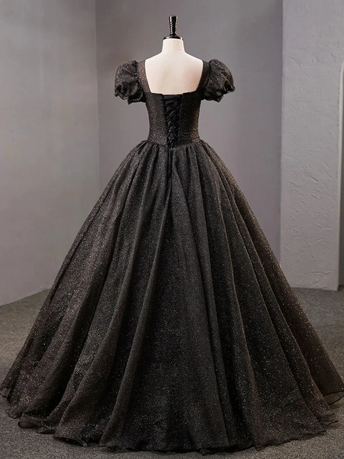 Elegant black ball gown with puff sleeves and lace-up back on mannequin at ZAPDRESS