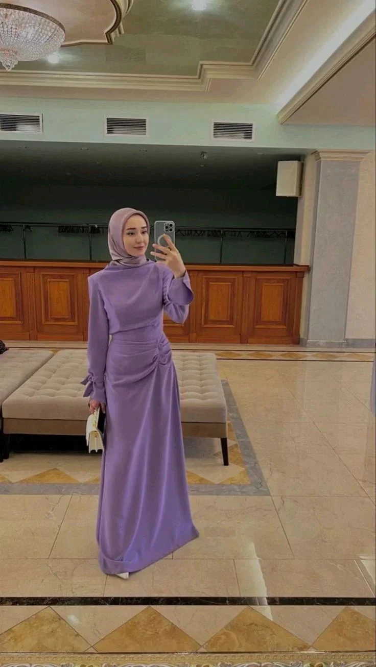 Woman in lavender modest dress and hijab taking a mirror selfie in a stylish lobby at ZAPDRESS