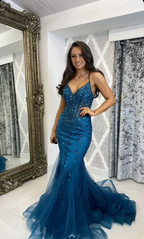 Woman in fitted blue mermaid sequin evening gown standing by ornate mirror, ZAPDRESS fashion
