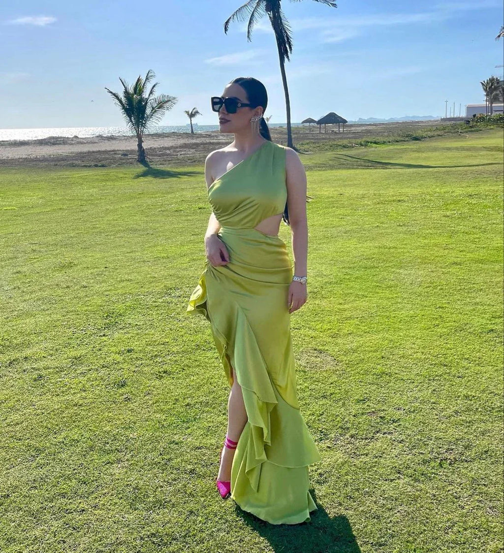 Woman in a lime green satin one-shoulder dress from ZAPDRESS on a sunny lawn by the beach