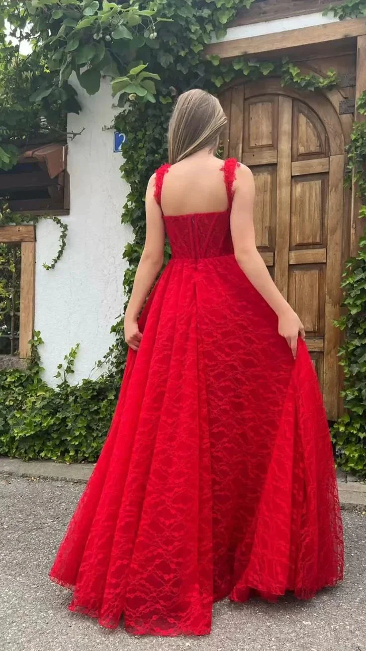 Woman in elegant red lace gown standing outdoors by a rustic wooden door, ZAPDRESS fashion