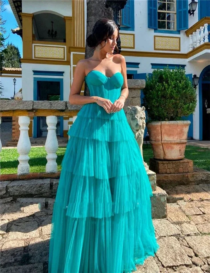 Woman in turquoise strapless tiered dress by ZAPDRESS standing outside a stylish villa
