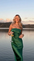 Woman in green strapless dress holding a drink by a lake at sunset, ZAPDRESS fashion