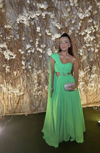 Woman in bright green evening gown with silver clutch, standing before floral backdrop, ZAPDRESS