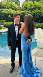 Young couple by pool, man in black tuxedo and woman in blue backless dress, prom style